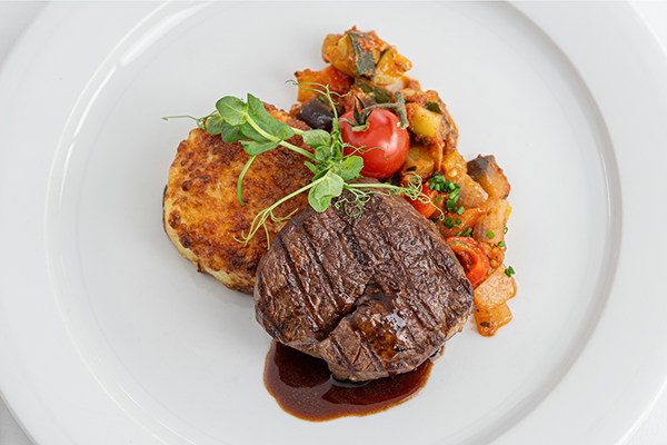Fillet of beef with side dishes, attractively arranged on a plate.