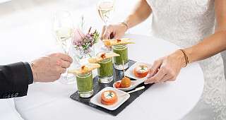 Bankett Apérohäppchen Apérohäppchen hübsch angerichtet auf einem Stehtisch, sichtbar sind zwei Paar Hände von Gästen, die sich bedienen