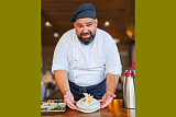 Portrait von Domenico, er zeigt knusprige Reisgalette mit geröstetem Rosenkohl, süss-saurem Teriyaki-Schaum und Katsuobushi