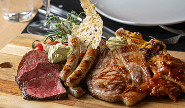 Holzplatte mit verschiedenen Fleischstücken vom Holzkohlegrill