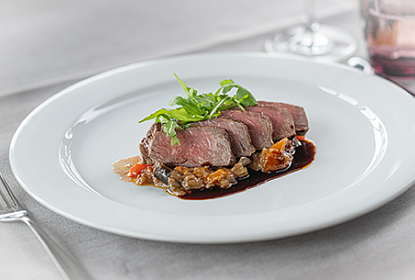 Schön angerichteter Teller mit Fleisch, Sauce und Gemüse